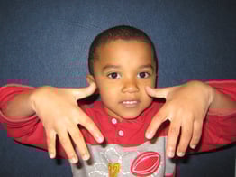 Kid wearing red and gray shirt with hands pointing down
