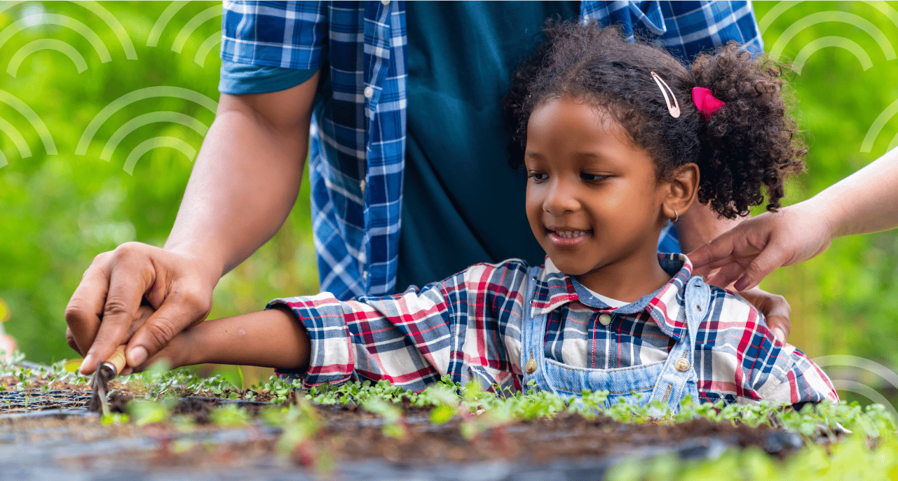 A young girl and an adult plant flowers in a flower bed